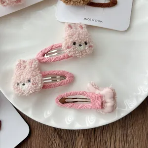 Detailed view of three pink plush bear and rabbit hair clips on a white ceramic plate