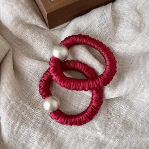 Close-up of deep wine red satin scrunchies with large elegant pearl embellishments