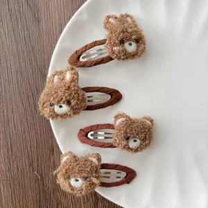 Detail of plush bear and rabbit hair clips with embroidery on a white ceramic plate
