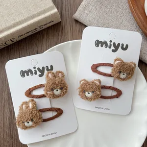 Detail of plush brown bear and rabbit hair clips on a white display card