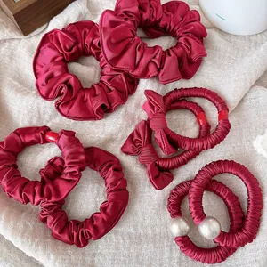 Close-up of burgundy satin scrunchies and bow hair ties with elegant white pearls