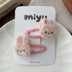 Detail of pink plush bunny hair clips on display card with soft textured fabric