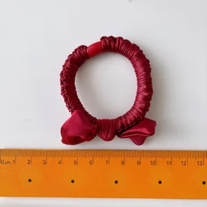 Elastic dark red satin scrunchie with bowknot detail shown with a 6cm measuring ruler