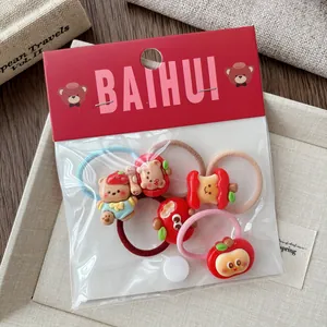 Close-up of cute red cartoon hair ties for girls with strawberry and apple charms on linen