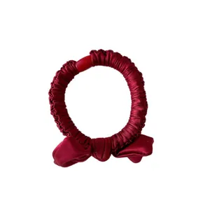 Elegant wine red satin bow scrunchie with pleated texture and decorative cylinder
