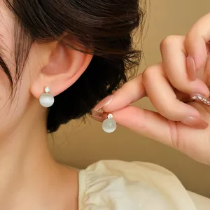 Detailed close-up showing elegant round cat eye stone stud earrings with zircon on a model.