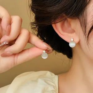 Close-up of elegant round cat eye stud earrings with sparkling zircon detail