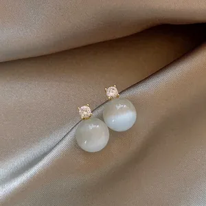 Macro view of elegant cat-eye stone stud earrings with sparkling zircon accents.