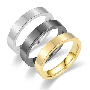 Dettaglio di tre anelli minimalisti in acciaio al titanio opaco in oro, argento e nero.