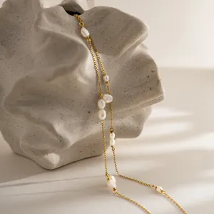 Close-up detail of a gold stainless steel necklace with irregular baroque pearls