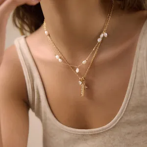 Layered gold-tone stainless steel necklace with pearls and '777' pendant on model