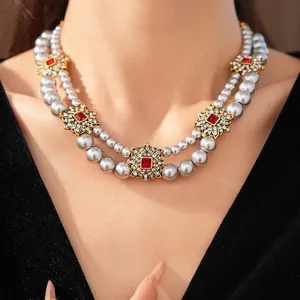 Vintage double-layer pearl necklace with gold flower pendants and red gems on model