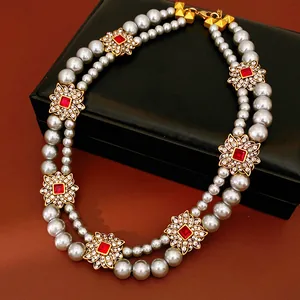Detailed view of a vintage double-layer pearl necklace with red stone flower accents.