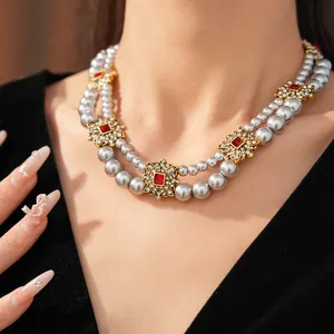 Detailed view of vintage double-layered silver pearl necklace with red floral gems on model