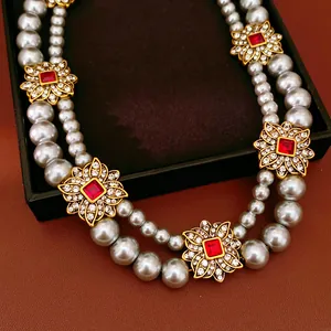 Close-up of vintage double-layered pearl necklace with red crystal flower charms