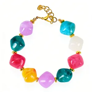Detail van meerkleurige acrylhars kralenarmband met een gouden karabijnsluiting sluiting