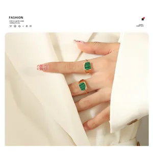 Detail of adjustable gold-plated rings with rectangular malachite green stones on hand