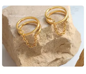 Dettaglio di orecchini a doppio anello in oro con nappe a catena su pietra