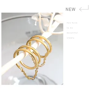 Dettaglio di un set di anelli a doppia catena dorata appesi a un ramo decorativo bianco
