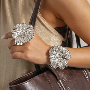 Detail view of oversized silver metallic flower ring and cuff bracelet set on model.