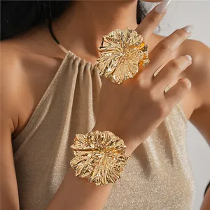 Detailed shot of golden metallic ruffled flower ring and matching wide cuff bracelet