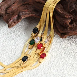 Collana a catena serpente dorata con pietre preziose ovali su sfondo in pietra rustica