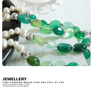 Detalle de cerca de perlas naturales y piedras de ágata verde en un collar de titanio