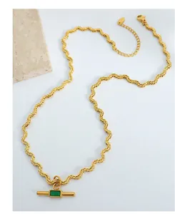 Detail of a wavy gold rope chain necklace featuring a vintage green stone pendant