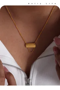 Dettaglio di una collana in titanio dorato con pendente rettangolare inciso e nappina