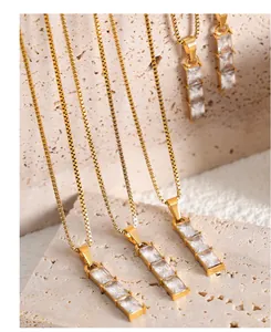 Detalle de cadenas box bañadas en oro de 18k y colgantes geométricos con circonitas
