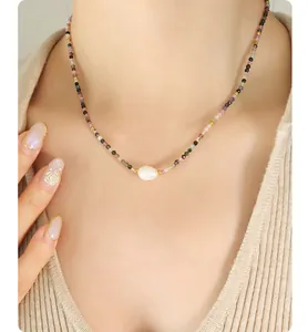 Dettaglio di una collana in pietre naturali colorate con un grande pendente di perla barocca