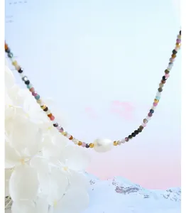 Dettaglio collana con perline di tormalina colorata, perla barocca bianca e accenti dorati