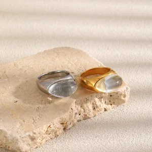 Detalle de anillos de acero inoxidable en oro y plata con piedras ovales de resina.