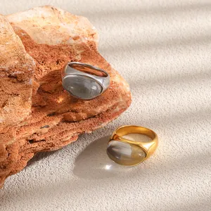 Primer plano de anillos de acero inoxidable oro y plata con piedras ovaladas de resina