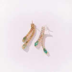 Detailed view of elegant dangling earrings with marquise green stones and clear zircons.
