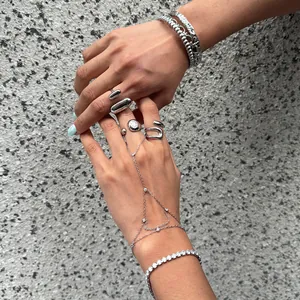 Gros plan de bagues et bracelets élégants en acier titane argenté portés aux mains