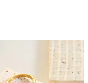Detailed view of a minimalist gold ring with a polished surface on textured stone