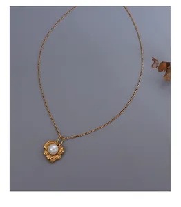 Makroansicht der goldenen Lotus-Halskette mit weißer Perle und feiner Gliederkette