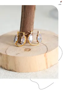 Detail of gold-plated hoop earrings featuring marquee cut zircon on wood display