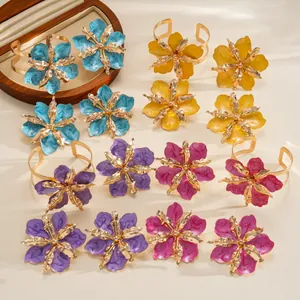 Close-up of vibrant floral jewelry set featuring gold metal bands and marbled enamel petals