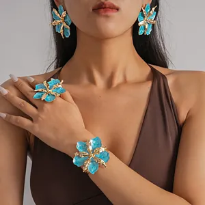 Detail view of metallic blue enamel flower jewelry set worn by a model