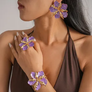 Close-up detail of purple and gold pleated flower jewelry set worn by an Asian model