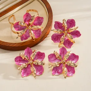 Detail of floral jewelry set with pink enamel petals and golden hollow metal centers