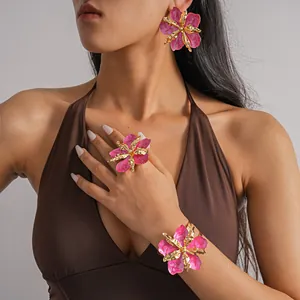 Close-up of pink and gold floral jewelry set including earrings, ring, and bracelet