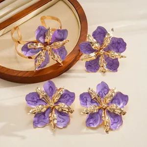 Detailed view of purple enamel flower jewelry set with gold-tone bangle and earrings