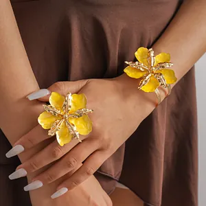 Detailed close-up showing metallic flower ring and gold cuff bracelet on a model