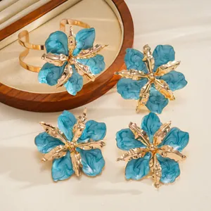 Detailed macro view of a blue enameled flower jewelry set with gold metal accents