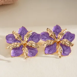 Macro view of purple enamel flower earrings featuring gold metallic texture and folds.