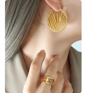 Macro shot of 18k gold plated hollow bamboo leaf hoop earrings and geometric ring