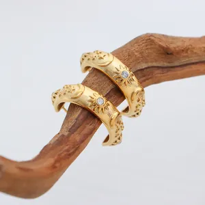 Luxury celestial sun and moon embossed gold hoop earrings with zircon stones on wood
